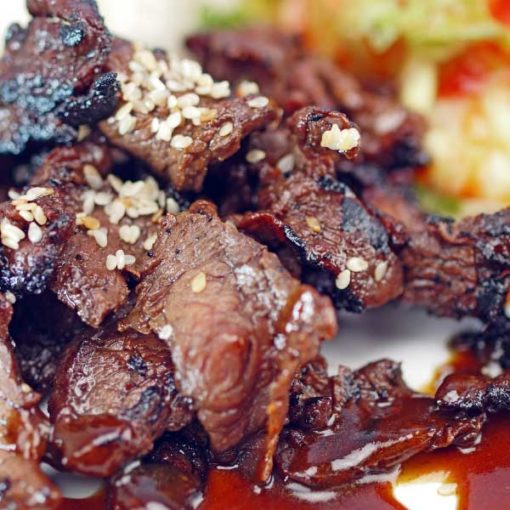 Bulgogi, Korean barbecue beef, enlarged to show the juicy texture of the beef topped with spicy barbecue sauce and sesame seeds.
