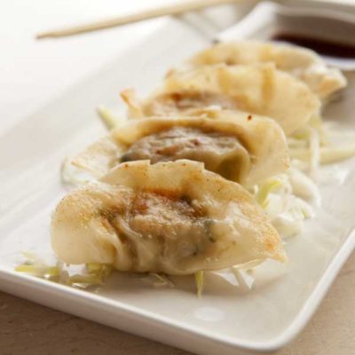 A plate of potstickers; wonton-wrapped chicken dumplings, served with a hearty asian dipping sauce.