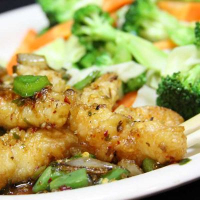 Spicy prawn stir fry plate, pictured with battered prawns and mixed vegetables, topped with a spicy stir fry sauce.