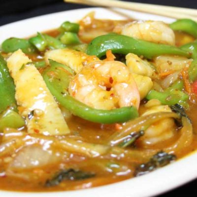 Thai spicy seafood stir fry, pictured with calamari, shrimp, sea scallops, and crab, as well as mixed vegetables in a spicy sauce.
